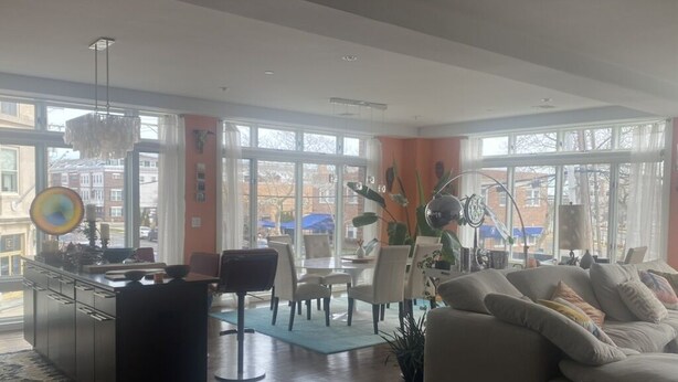 A spacious living room with a large window, a dining area, and a modern kitchen.