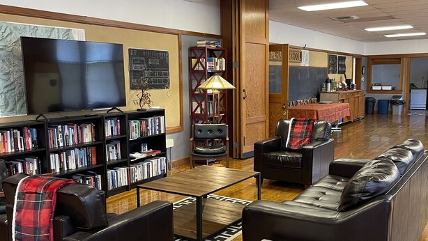 A library with bookshelves, a television, a coffee table, and leather sofas. - The Mineral Schoolhouse (Mineral)