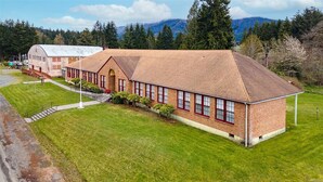 A large brick building with a sloped roof, surrounded by a well-maintained lawn and trees. - The Mineral Schoolhouse (Mineral)
