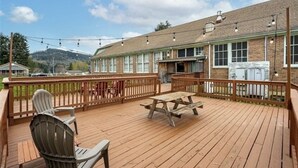 A wooden deck with a picnic table and chairs, a brick building with large windows, and a mountain in the background. - The Mineral Schoolhouse (Mineral)