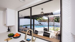 Una cocina moderna con un amplio ventanal que da a una zona de piscina.