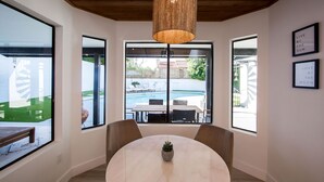 Una habitación moderna con una mesa redonda, ventanas amplias y una lámpara colgante.