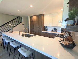 A modern kitchen with a large island, bar stools, wooden cabinets, and a built-in oven. - Mountain Modern Retreat - Walk to Park City Mtn - 2 King Suites - Pool & Hot Tub (Park City)