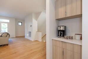 Une cuisine moderne dotée d’une machine à café intégrée, d’un plan de travail blanc et d’un meuble en bois.