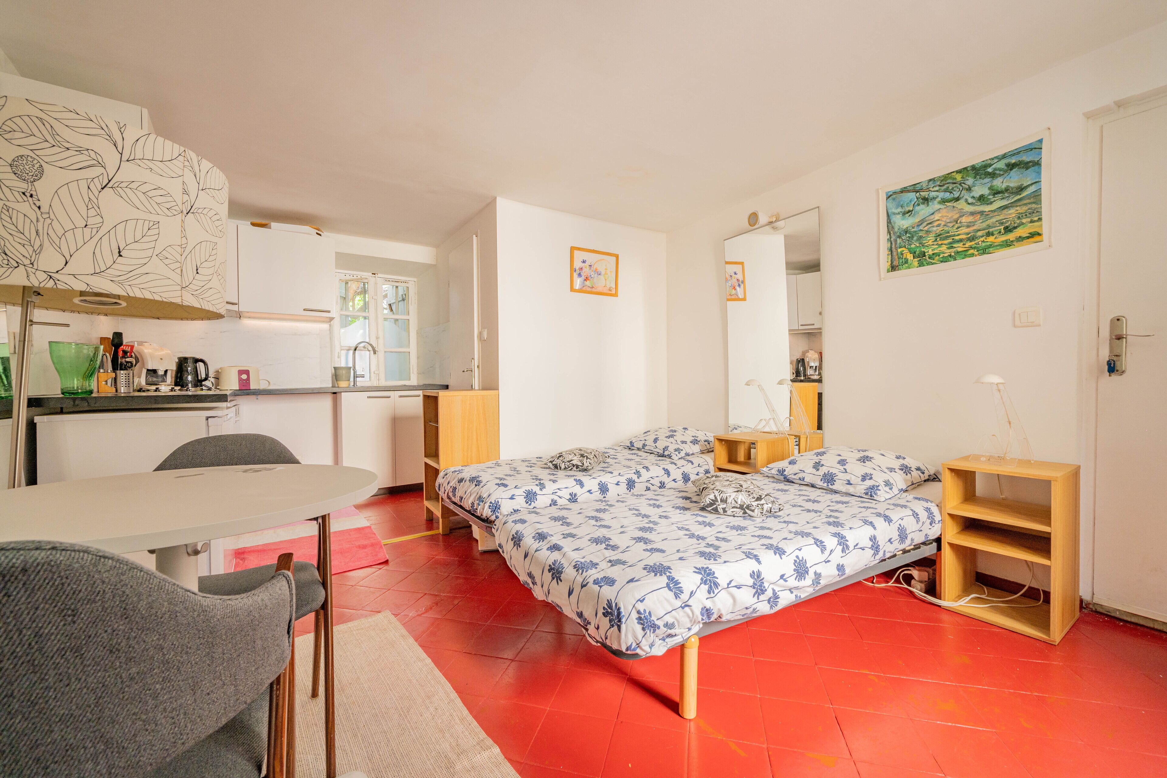A compact room with a bed, a small desk, and a kitchenette.
