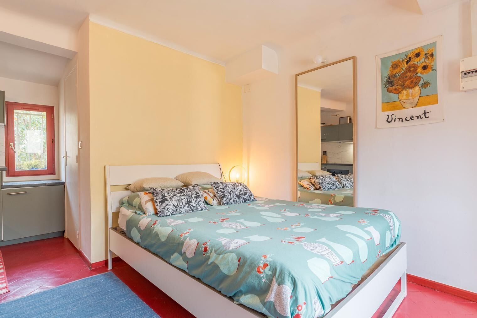 Un dormitorio con cama, espejo, ventana y puerta.