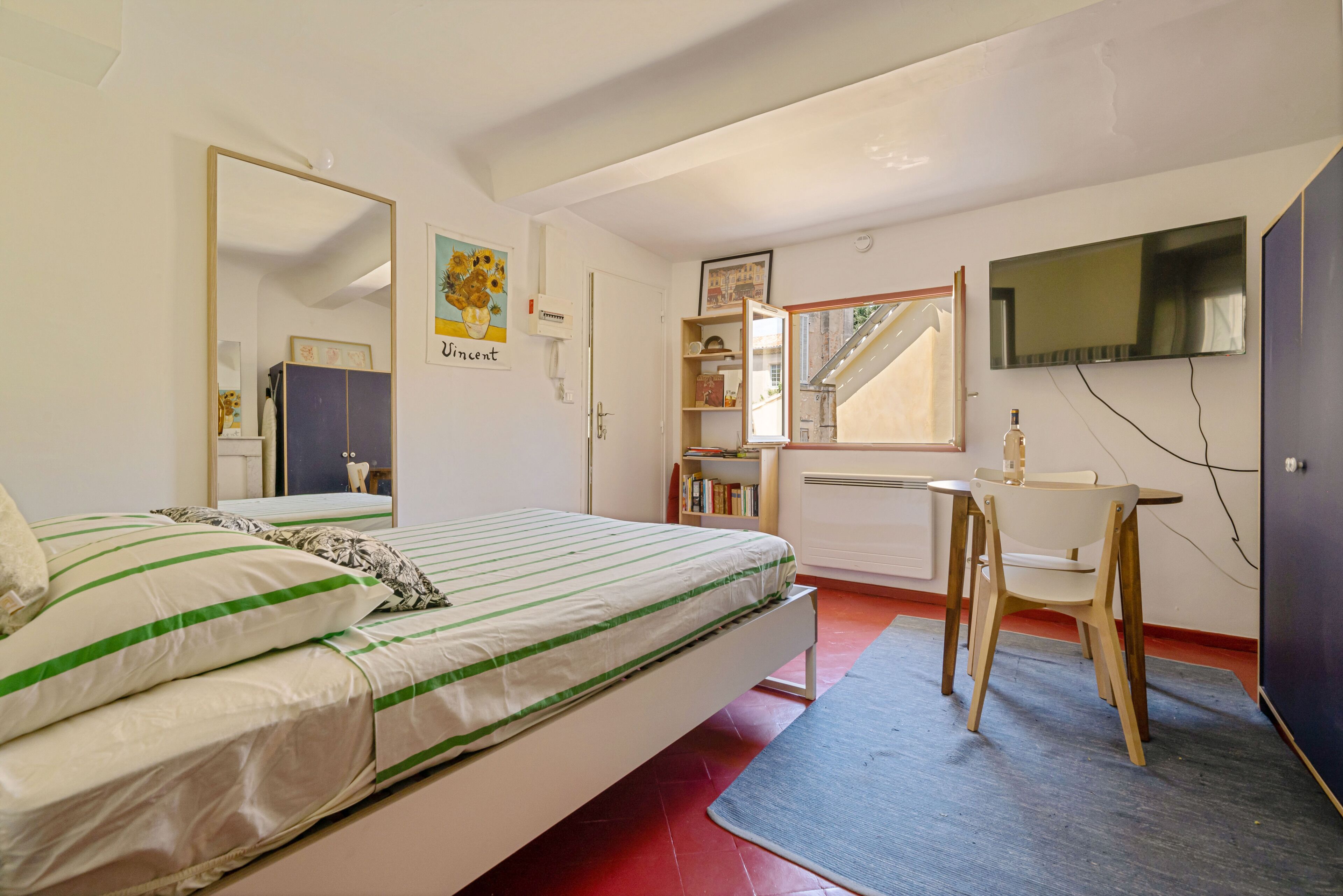 A bedroom with a bed, a desk, a chair, a TV, and a bookshelf.
