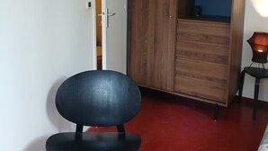 Una habitación con un armario de madera, un cuadro en la pared y un suelo rojo.