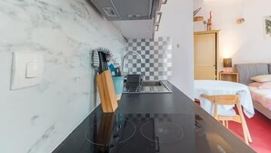 Una cocina compacta con mostrador negro, un lavamanos y un protector contra salpicaduras de mármol.