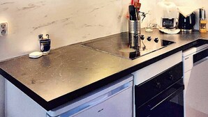 Una cocina compacta con encimera negra, electrodomésticos de acero inoxidable y salpicadero blanco.