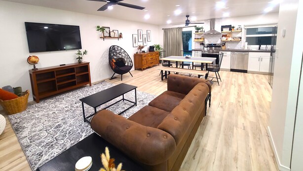A modern living room with a sofa, coffee table, and a TV. There is a dining area with a table and chairs, and a kitchen with cabinets and appliances. - Beautiful, Cozy, and Spacious home- 3 mins from downtown (Oberlin)
