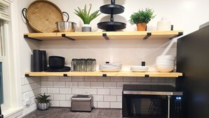 A kitchen with two wooden shelves, a toaster, a microwave, and a sink. - Beautiful, Cozy, and Spacious home- 3 mins from downtown (Oberlin)