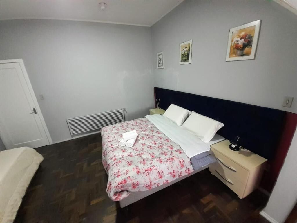A bedroom with a bed, bedside tables, a heater, and wall art.