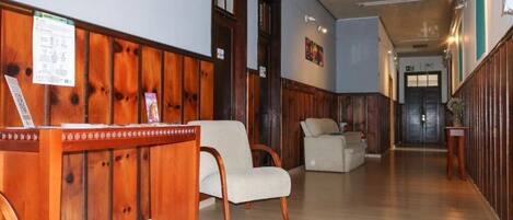 A reception area with a wooden reception desk, two upholstered chairs, and a hallway leading to a door.