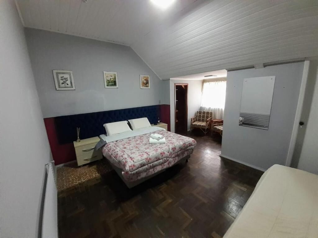 A bedroom with a bed, a nightstand, a chair, and a door leading to another room.