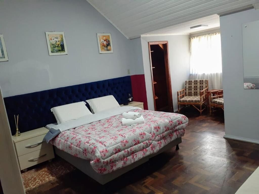 A bedroom with a bed, a nightstand, a chair, and a door leading to another room.