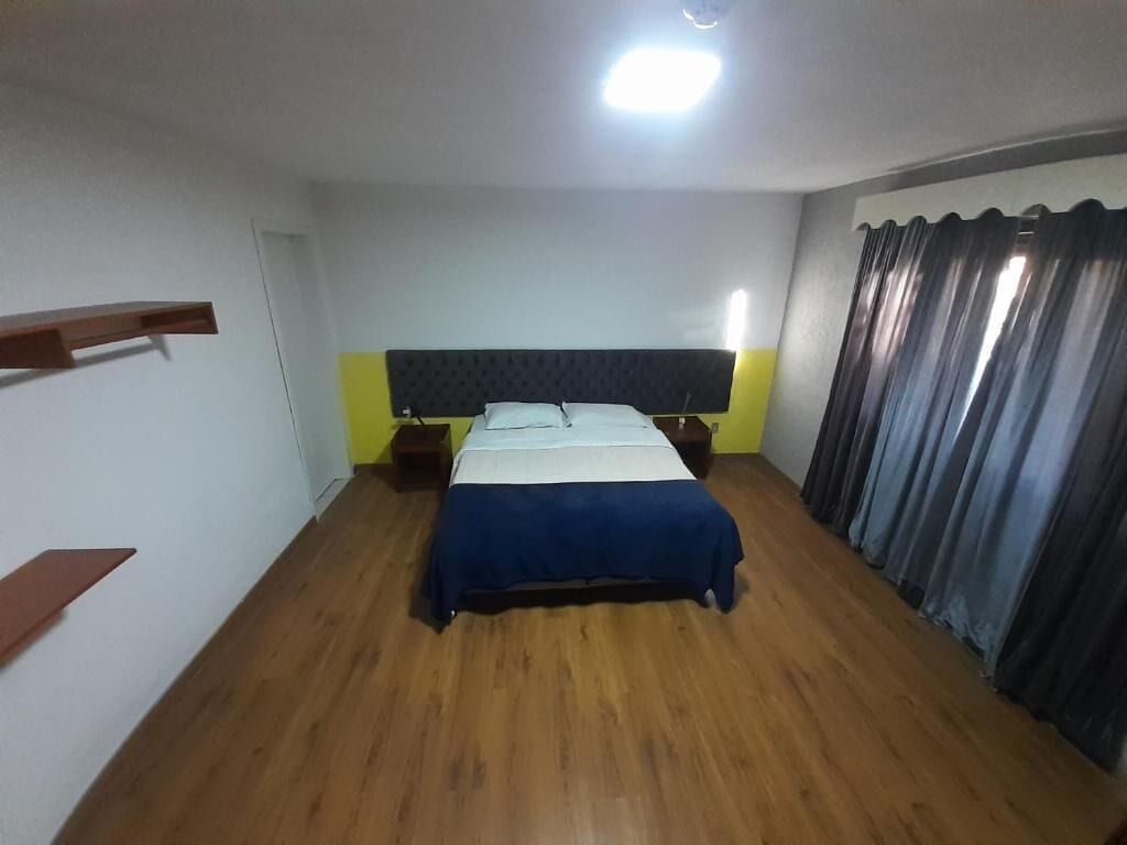 Een slaapkamer met een bed, houten vloer en een hoofdeinde.