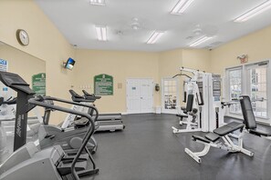A gym with treadmills, weight machines, and a wall clock.