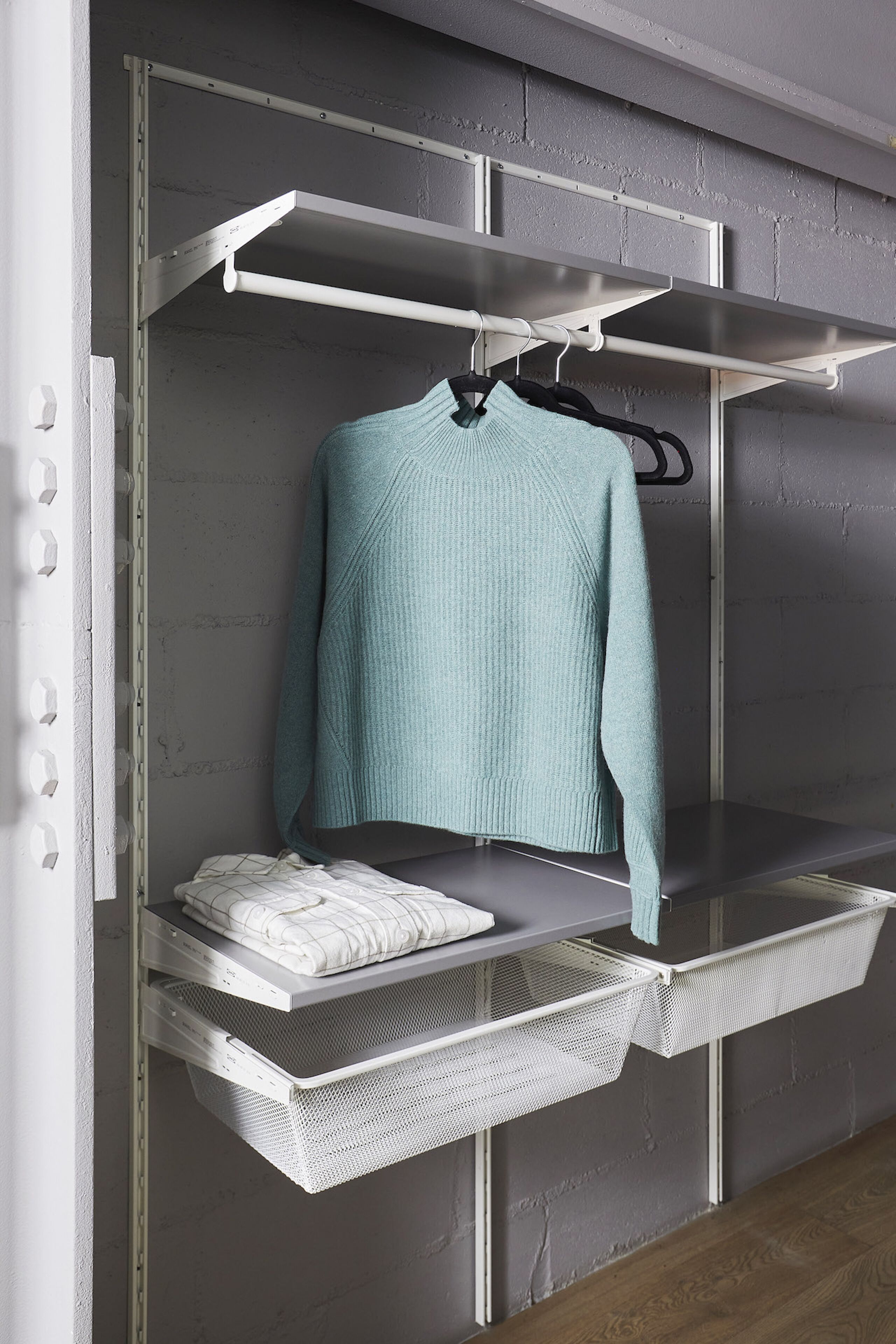 Un armario moderno con estantes abiertos, una barra para colgar ropa y una cesta de malla para almacenamiento.
