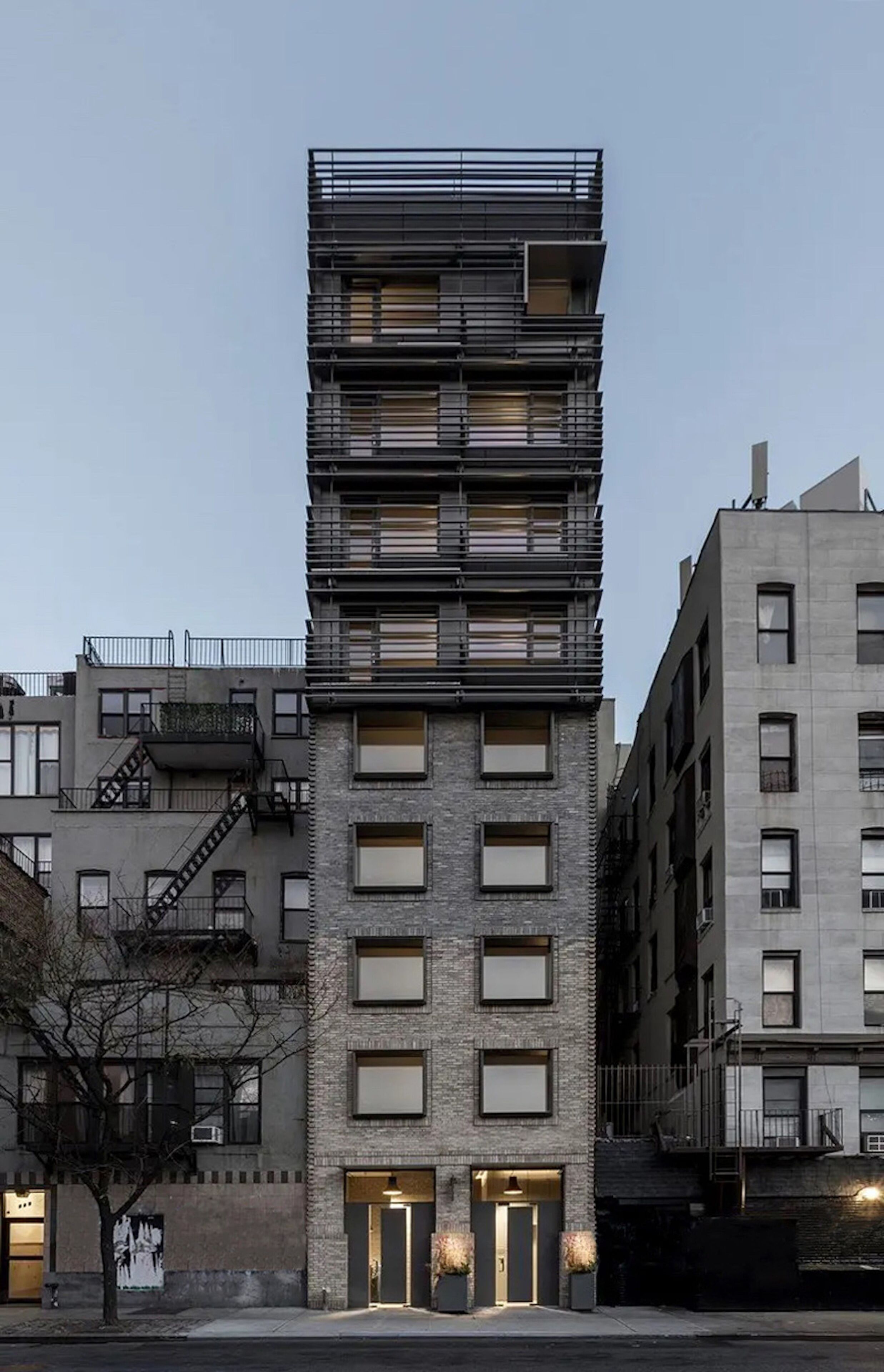 Un immeuble à plusieurs étages, doté d’un design moderne, qui combine des éléments en brique et en métal, et qui présente une série de balcons aux étages supérieurs.