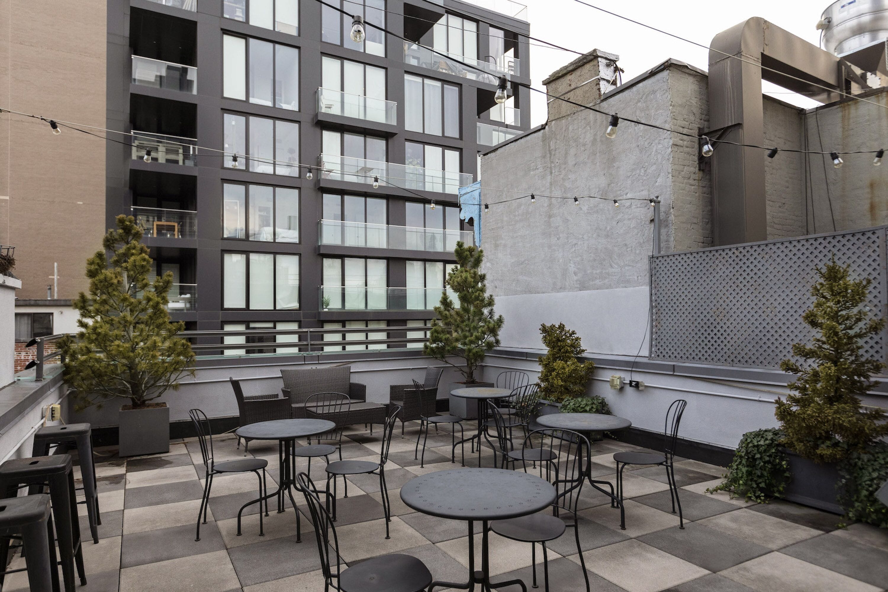 En takterrass med utomhusmöbler, krukväxter och en modern byggnad i bakgrunden.