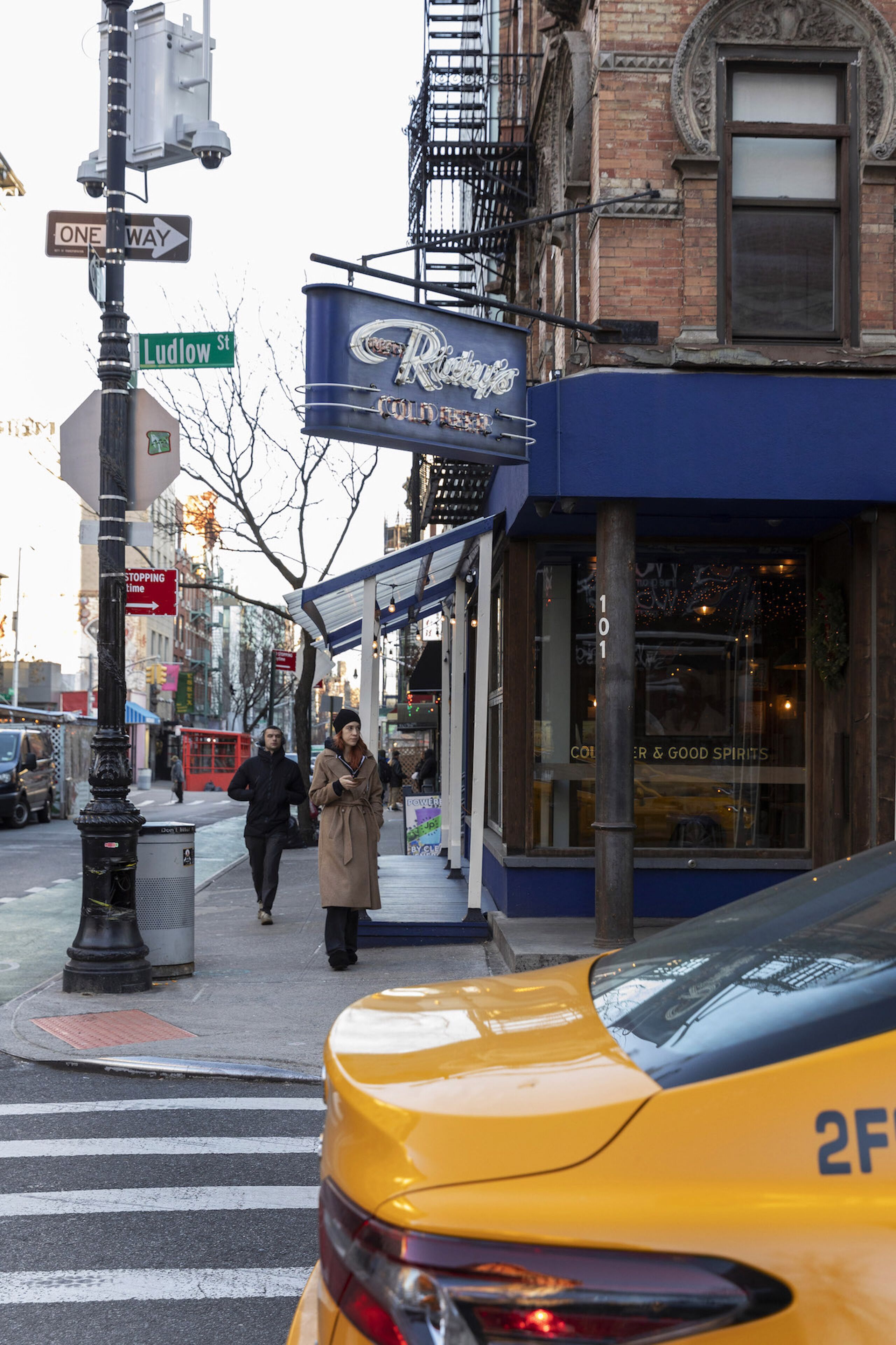 A street corner with a taxi, a storefront with a sign reading "Ridgeway," and a pedestrian crossing.