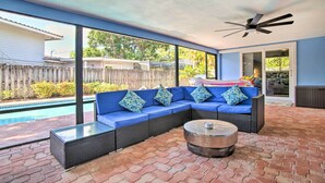 Un'area patio coperta con divano blu, tavolino rotondo e ventilatore a soffitto.
