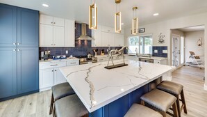 Een moderne keuken met een groot eiland, hanglampen en uitzicht op buiten.