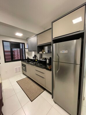 A modern kitchen with stainless steel appliances, a black countertop, and a built-in oven. - Ap. Palmas Golden: Piscina, Praia e Brinquedoteca (Governador Celso Ramos)