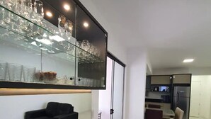 Ett modernt kök med ett inbyggt kylskåp, en matplats med bord och stolar samt ett glasskåp för att visa upp glasvaror.