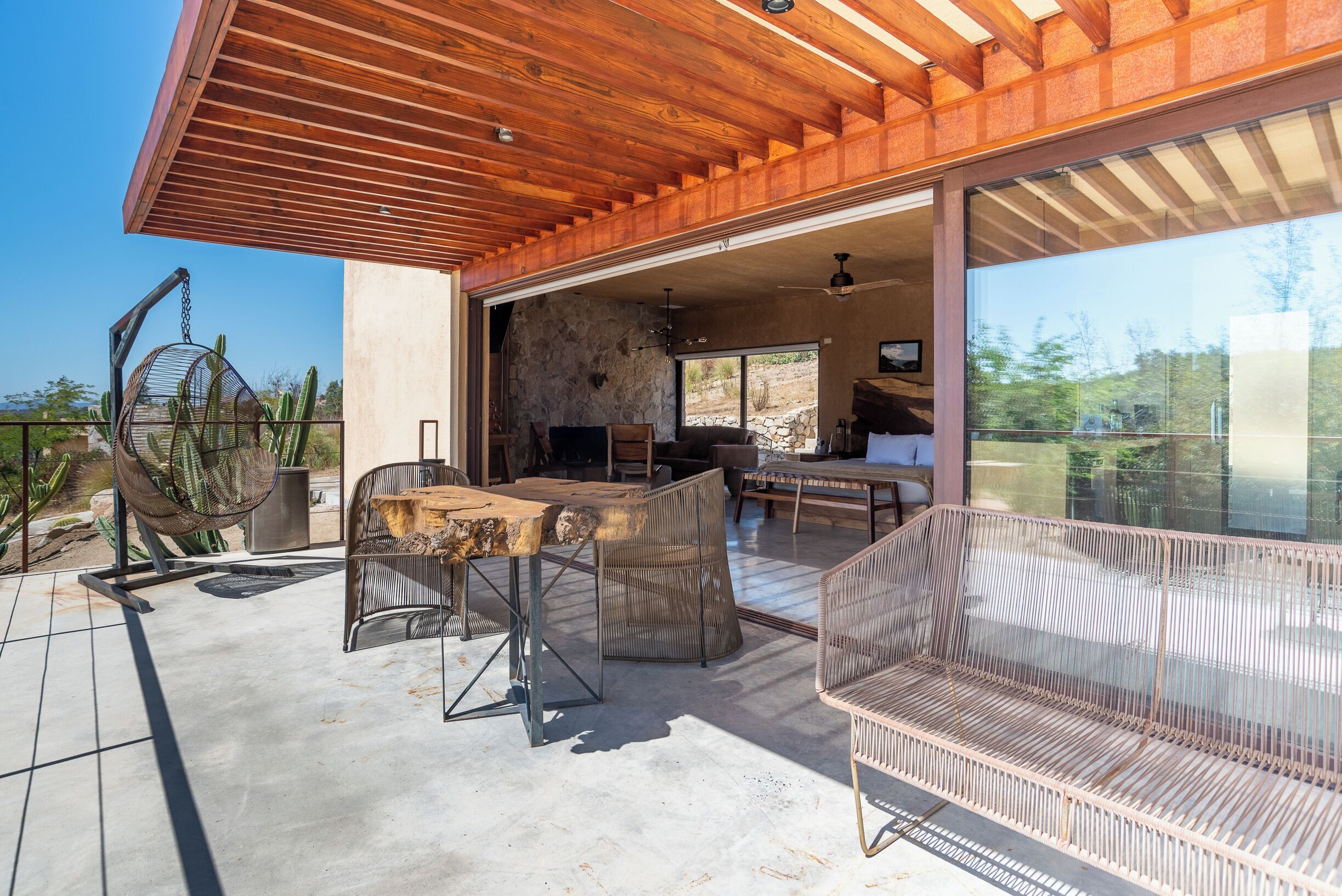 An open patio with a dining table, chairs, and a hanging chair.