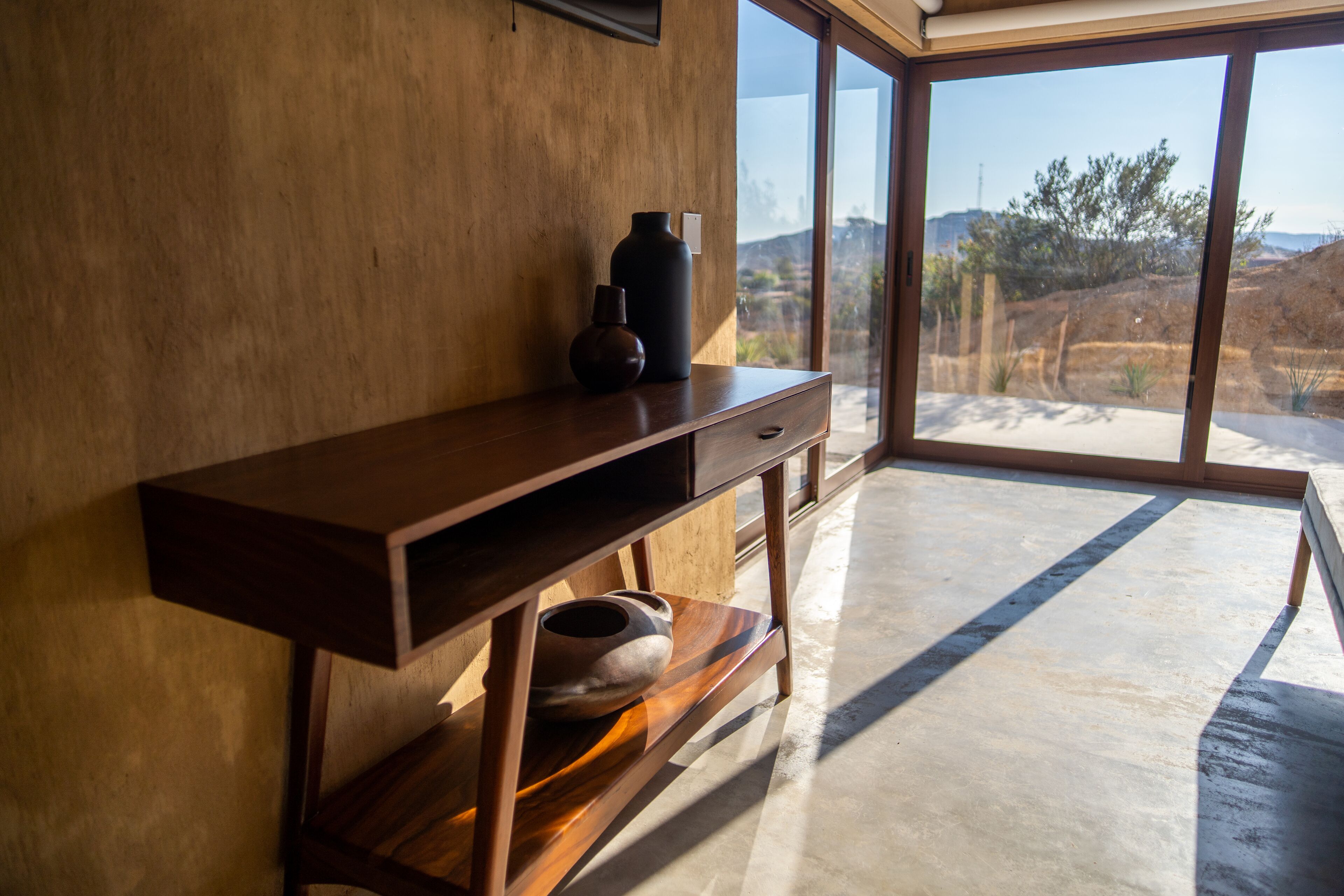 Una habitación moderna con un escritorio de madera, un florero y un cuenco.