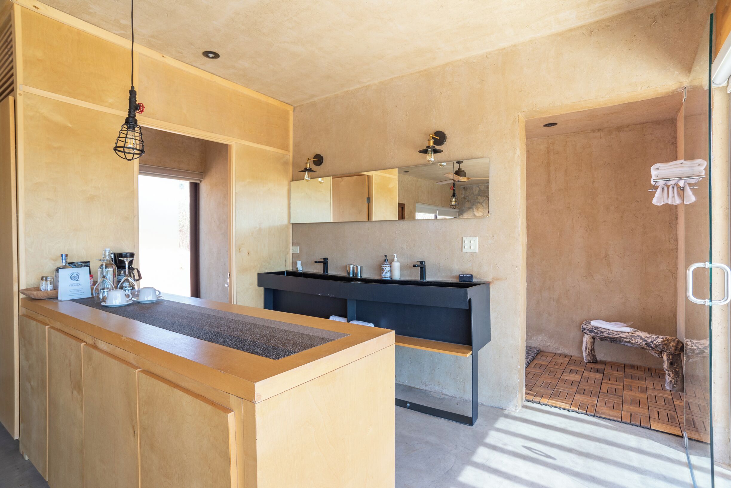 A modern bathroom with a wooden vanity, a black sink, and a shower area with a bench.
