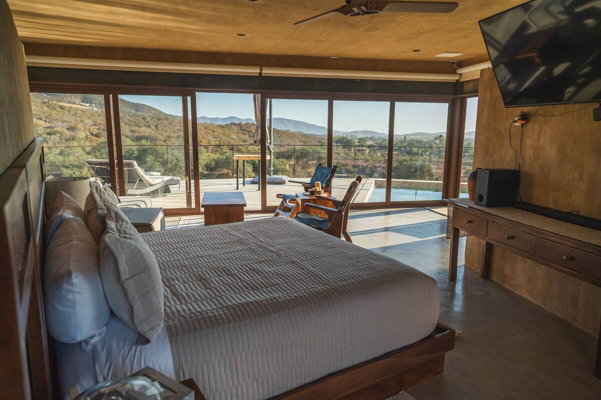 Un dormitorio con una cama grande, un escritorio, una silla, un televisor y vistas al exterior.