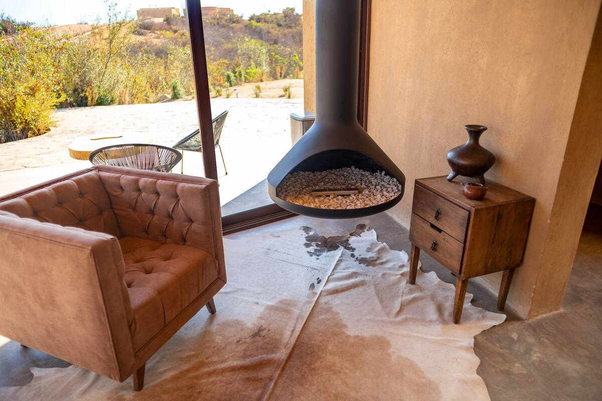 Una habitación con un sillón de cuero, una mesita de madera y una chimenea grande con un marco de piedra.