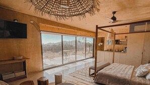 Un vaste espace de vie doté d’une grande fenêtre, d’un plafond en bois et d’un canapé moderne.