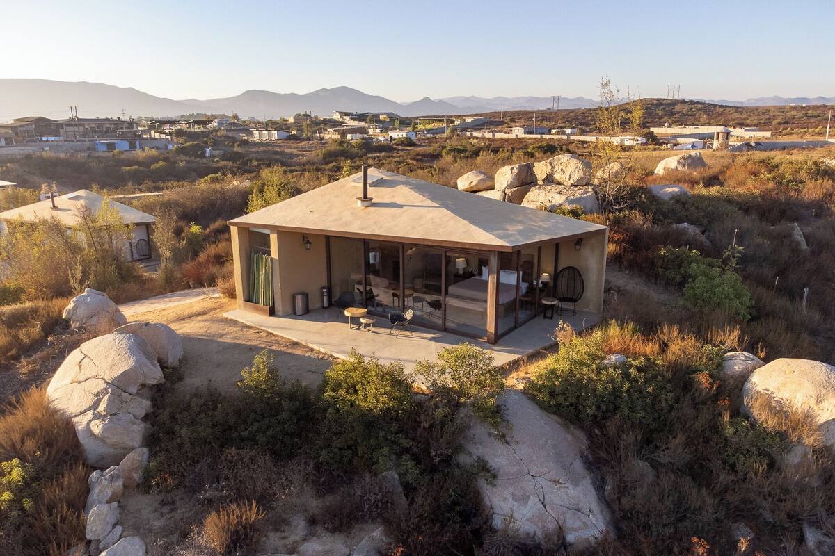 Una casa moderna con techo plano, ventanas amplias y un patio.