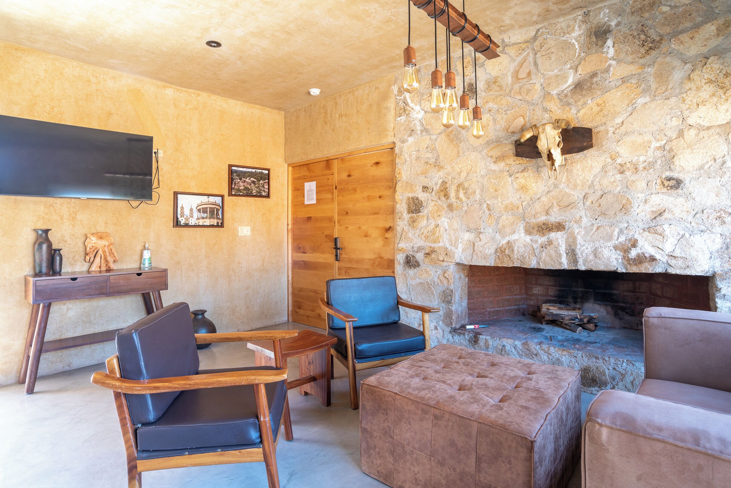 Una sala de estar acogedora con chimenea de piedra, muebles de madera y un televisor de pantalla plana montado en la pared.
