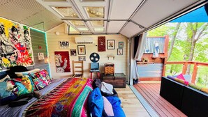 Ein geräumiges Schlafzimmer mit einem großen Bett, einer Holzdachterrasse und Blick auf Bäume.