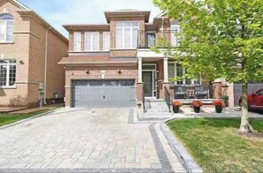 Stunning home with a central entrance, covered porch, and beautifully manicured lawn.