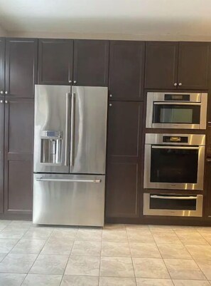 Enjoy cooking in this fully equipped kitchen with a refrigerator, two ovens, and dark-colored cabinets.