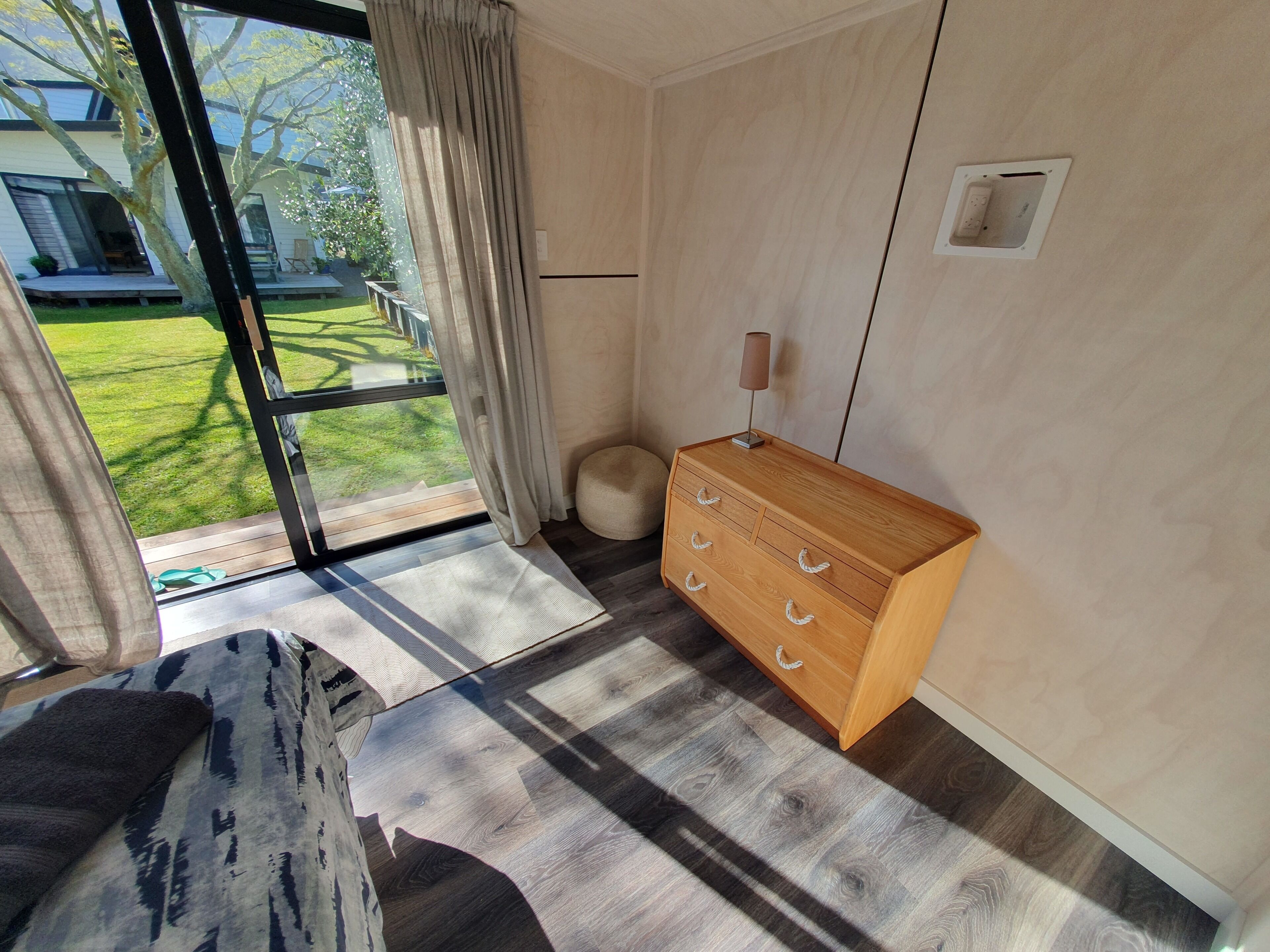 Ein modernes Zimmer mit einem großen Fenster, einem Holzkleiderschrank und einem gemusterten Teppich.