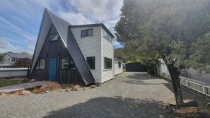 Uma casa moderna com um telhado triangular distinto e uma entrada com calçamento de pedras.