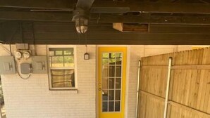 Un espace de stationnement couvert, doté d’un sol en béton, d’une porte jaune et d’une clôture en bois.