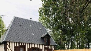 Une maison traditionnelle à colombages, dotée d’un toit en pente et d’un jardin clos.