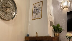 Un salon avec une cheminée, une horloge et un téléviseur fixé au mur.
