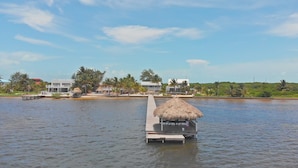 A waterfront property with a thatched-roof structure on a dock, a pool, and buildings with balconies overlooking the water. - Ocean Front  Home with pier. (San Pedro Ambergris Caye)
