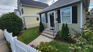 A two-story house with a front porch, a small front yard, and a white picket fence. - Minutes to Walnut Beach, newly renovated 3 bedroom home (Milford)