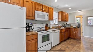 A kitchen with wooden cabinets, white appliances, and a tiled floor. - Minutes to Walnut Beach, newly renovated 3 bedroom home (Milford)