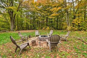 Relax by the fire pit surrounded by Adirondack chairs on a serene grassy lawn.